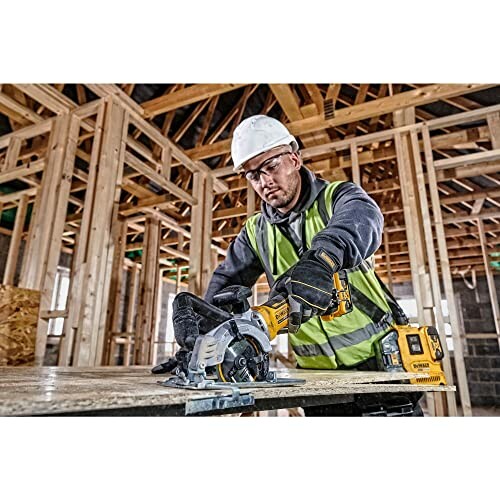 Construction worker using a circular saw on a wood panel in a building frame.