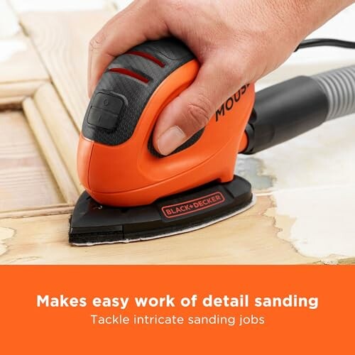 Hand using an electric detail sander on wood surface.