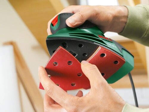 Person changing sandpaper on a handheld electric sander.